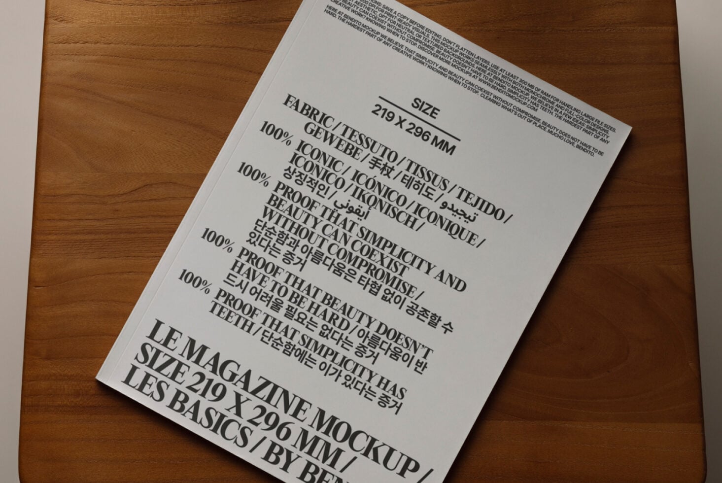 Light gray magazine mockup tilted on wooden surface with multilingual text