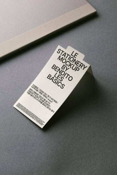 Overhead shot of cream tag mockup on gray surface with beige stripe backdrop