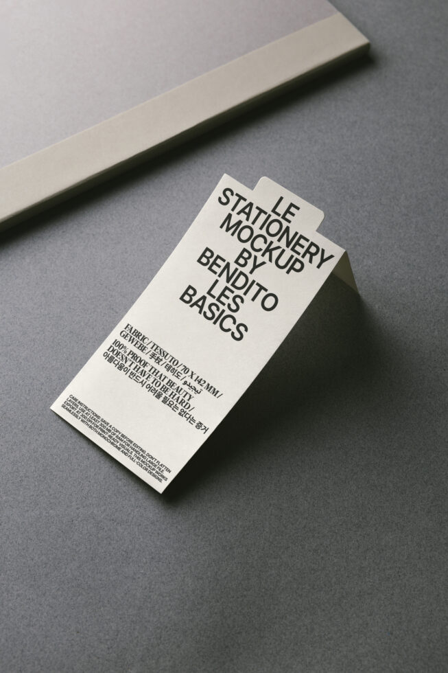 Overhead shot of cream tag mockup on gray surface with beige stripe backdrop