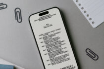iPhone mockup with cream screen filled with product details, cable connected, flat lay with paper backdrop