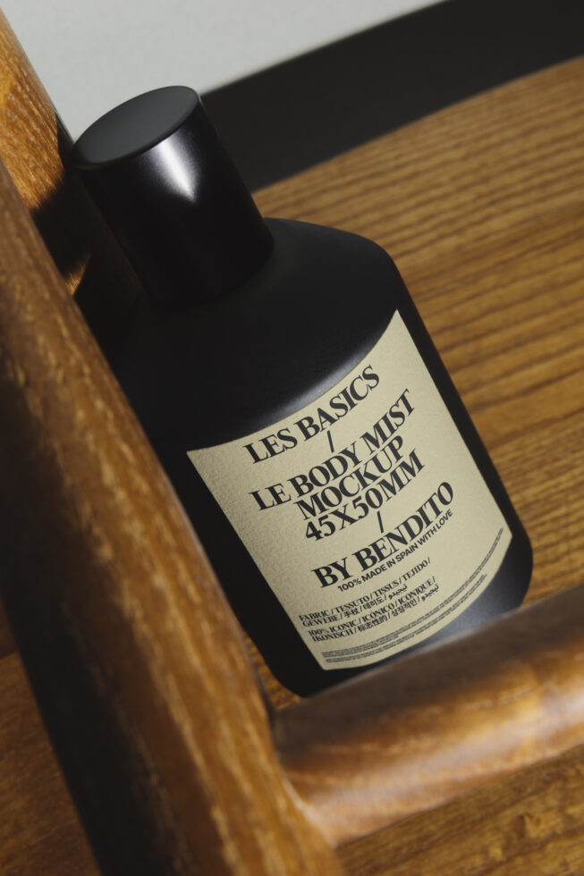 Black mist bottle with cream label on wooden surface, angled shot