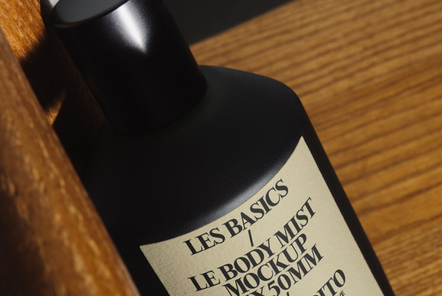 Black mist bottle with cream label angled on wooden surface in natural light