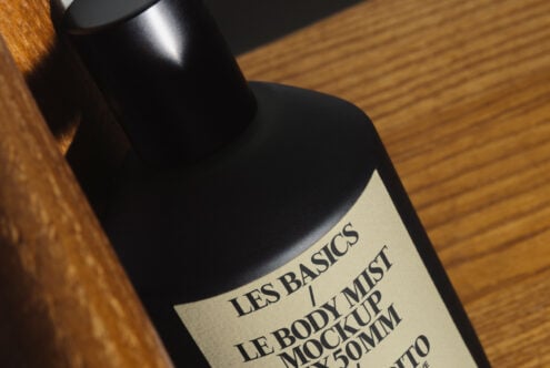 Black mist bottle with cream label angled on wooden surface in natural light