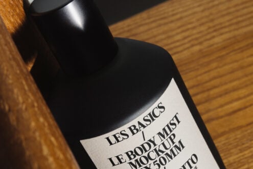 Black mist bottle with cream label on wooden surface casting soft shadow