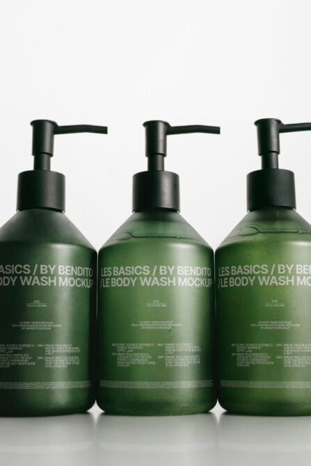 Three dark pump bottle mockups filled with green liquid on white background
