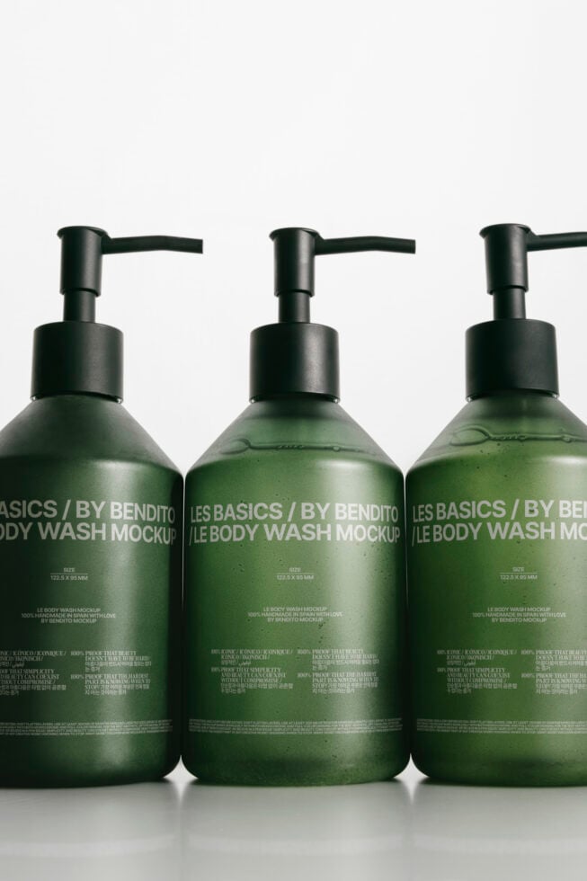 Three dark pump bottle mockups filled with green liquid on white background