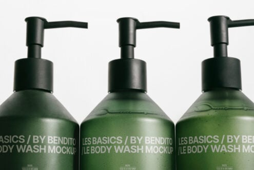 Close up of three dark pump bottles with green liquid, black pump tops visible