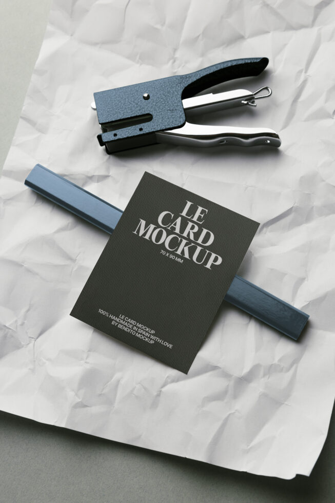 Business card mockup in black with blue stapler on crumpled white paper surface