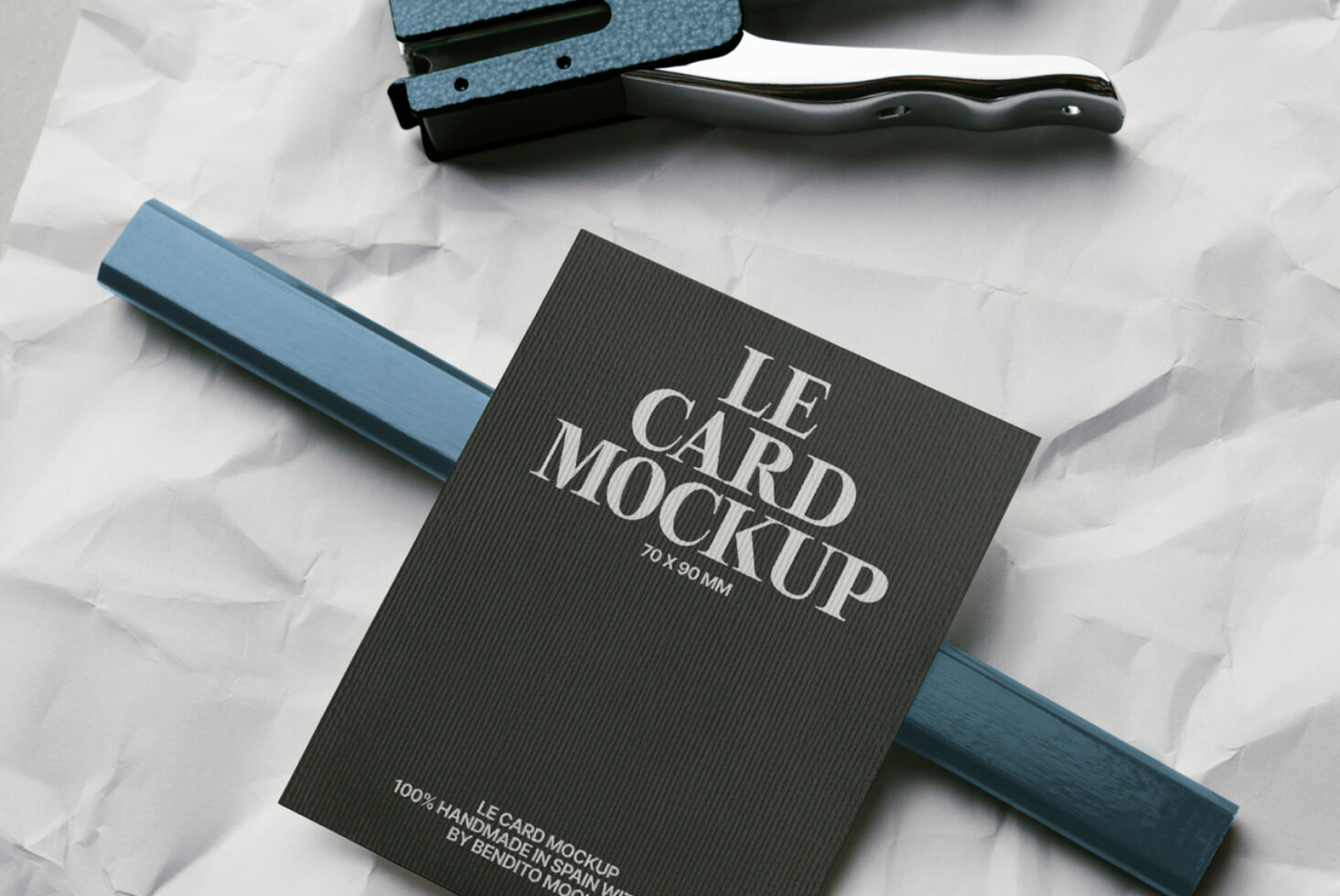 Dark card mockup with blue fabric swatch, stapler, black handle on crumpled paper