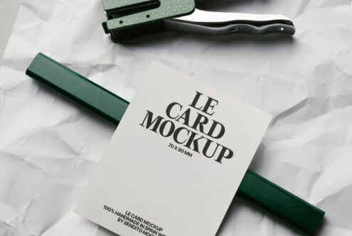 White card mockup with green fabric swatch, stapler, black handle on crumpled paper