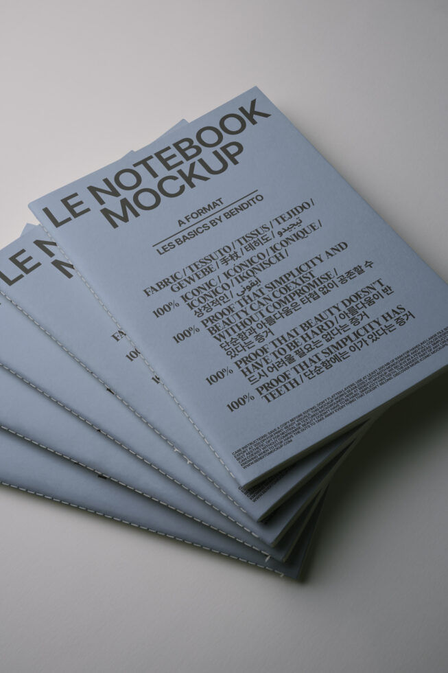 Stacked pale blue notebooks with stitched binding showing text layout mockup