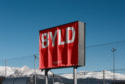 Bold red billboard with BYLD text against snowy mountain backdrop