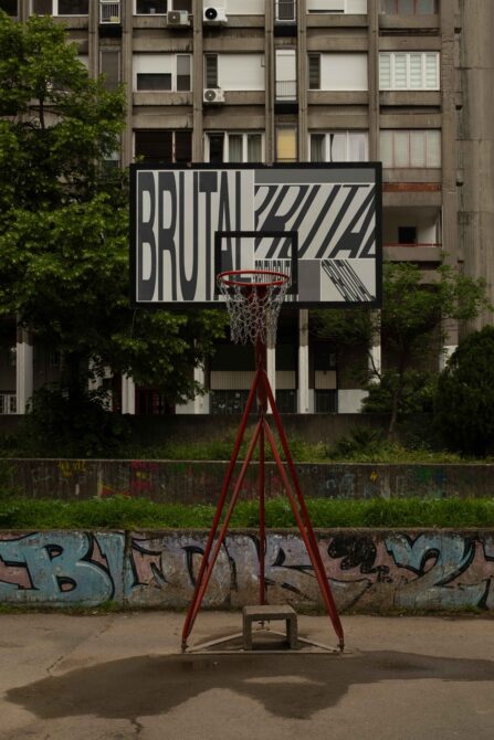 Basketball hoop with black poster mockup against brutalist apartment building