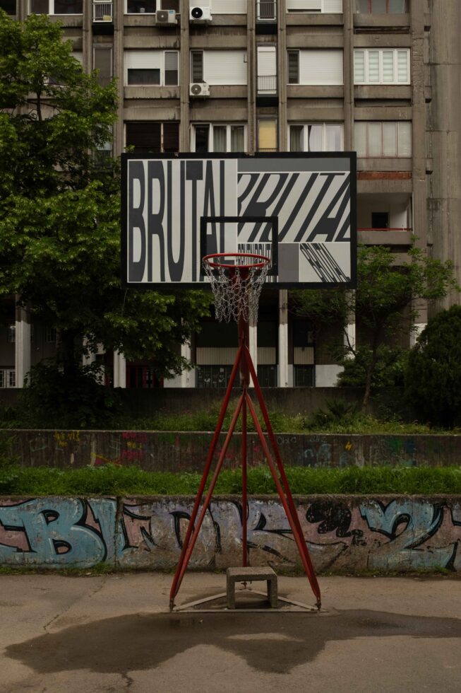 Basketball hoop with black poster mockup against brutalist apartment building