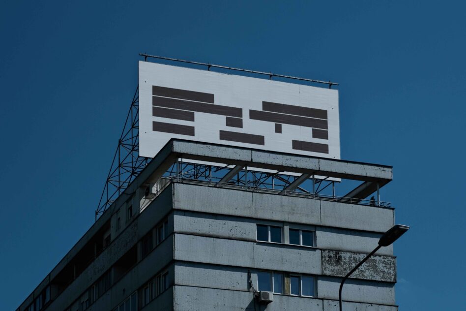 Brutalist concrete building with blank billboard against clear blue sky