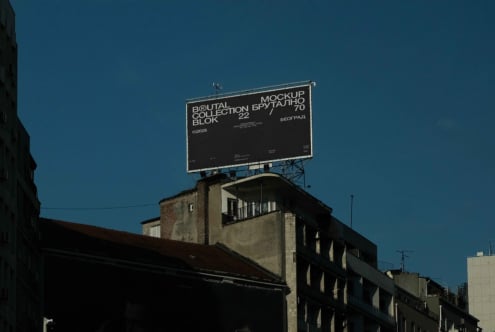 Dark billboard mockup displaying Brutal Collection branding on building against blue sky