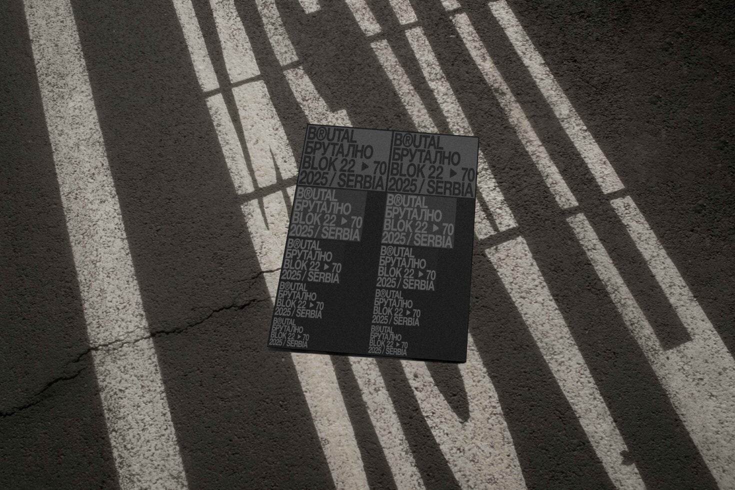 Black poster mockup on pavement with dramatic striped window shadows