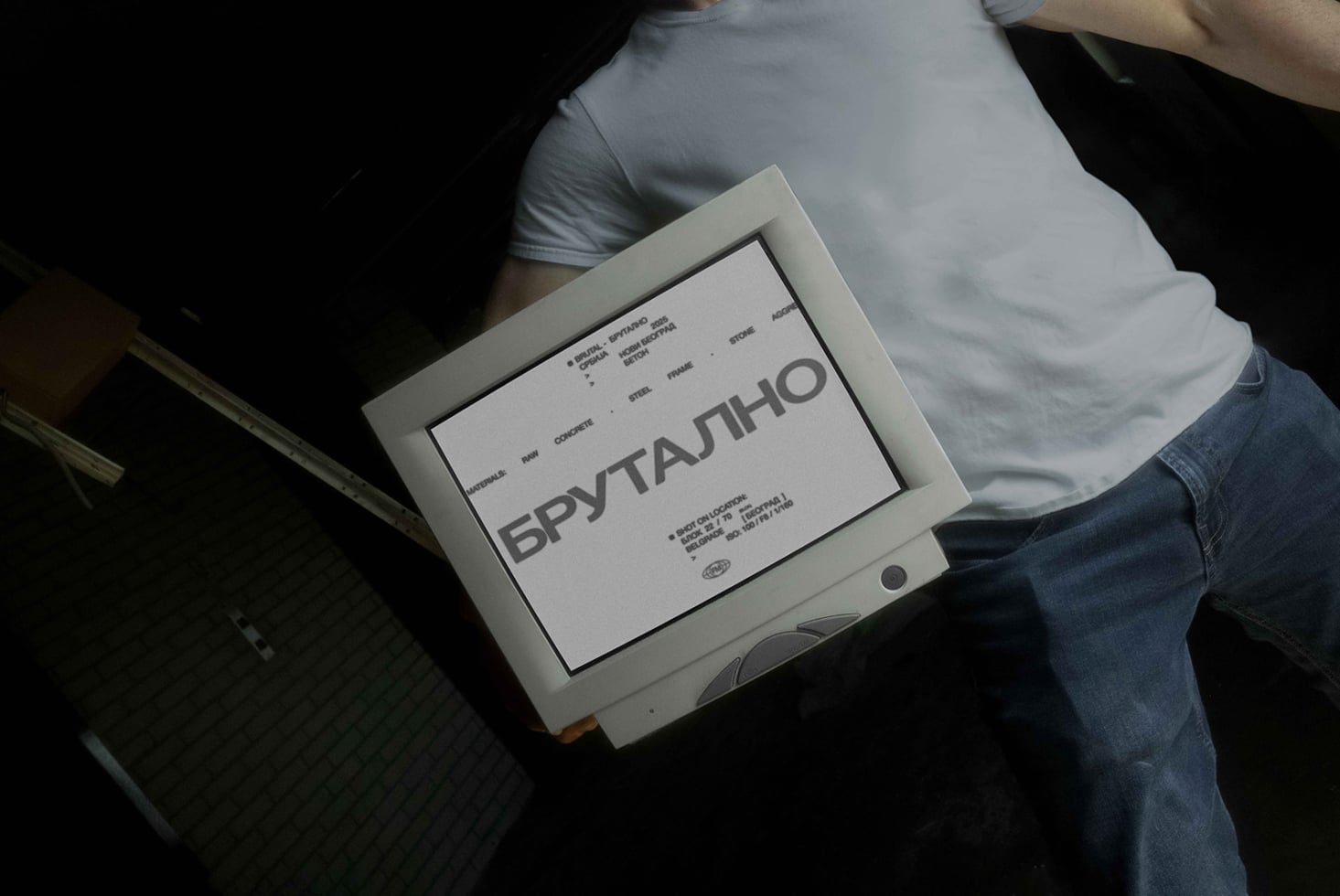 Brutal event poster held by person in light frame against dark background