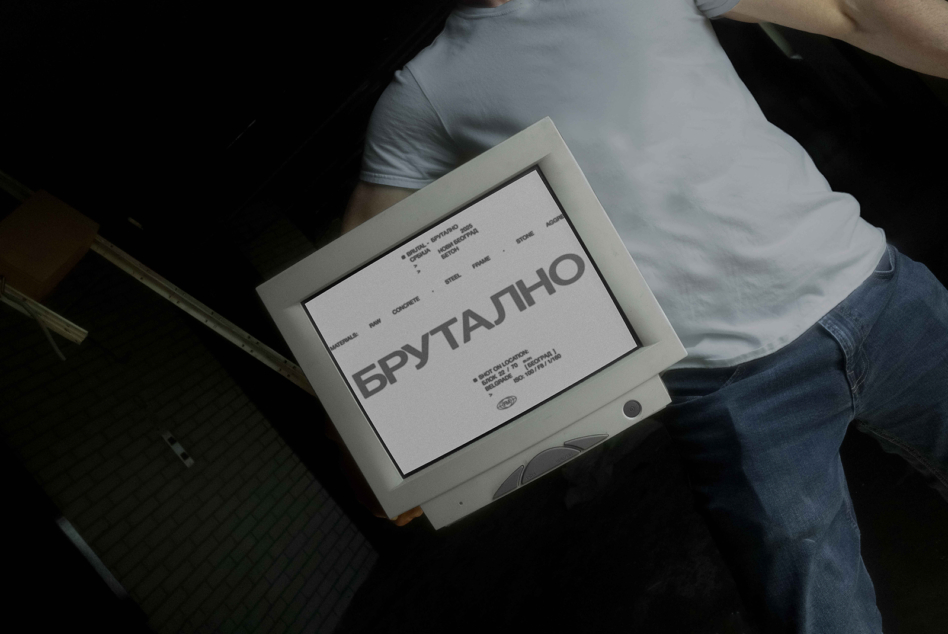Brutal event poster held by person in light frame against dark background