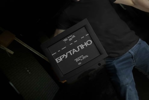 Brutal event poster held by person in dark frame against black background