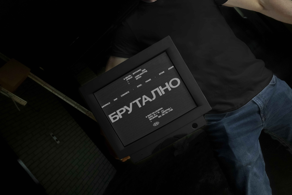 Brutal event poster held by person in dark frame against black background