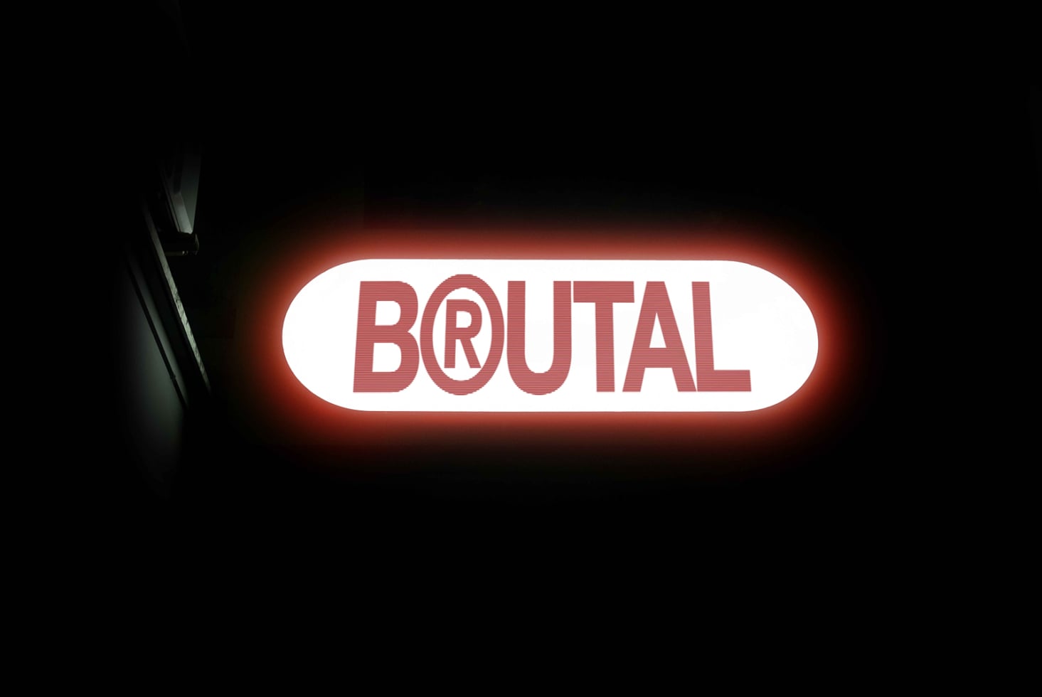 Glowing red neon sign reading BRUTAL on white rounded background