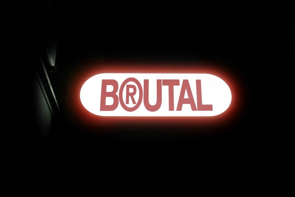 Glowing red neon sign reading BRUTAL on white rounded background