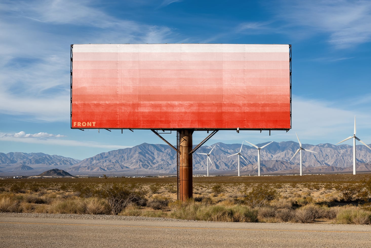 Gradient red billboard fading to white, desert view with spinning wind turbines