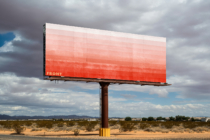 Red to white gradient billboard on rust support pole in wide open desert landscape