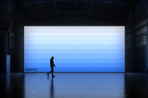 Person running past blue lit billboard in dark warehouse, minimal aesthetic