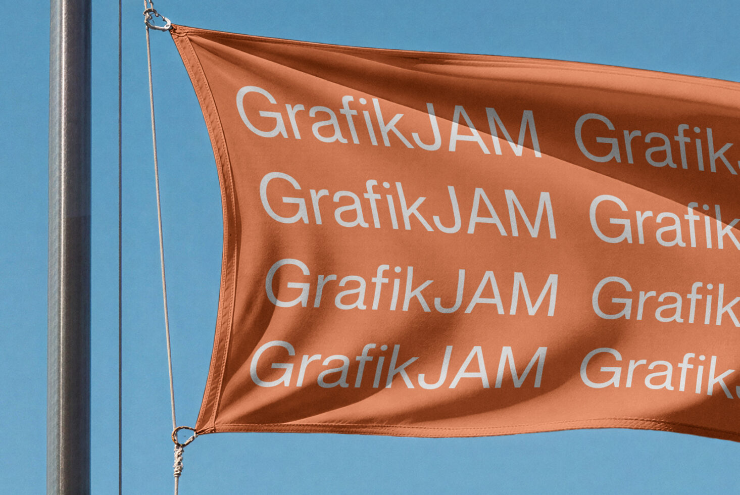 Orange flag mockup waving on pole with repeated text pattern against clear blue sky