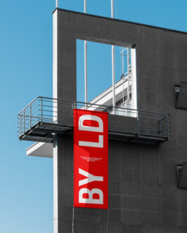Red vertical banner mockup displayed on industrial concrete building exterior