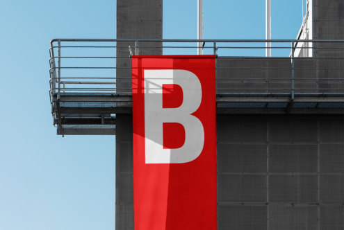 Red banner with large B letter overlapping white on dark building