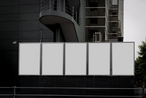 Five blank billboard panels on urban storefront with modern architecture backdrop