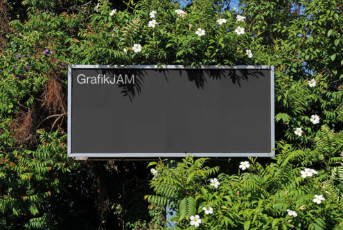 Dark gray billboard mockup nestled in lush green foliage with white blooms
