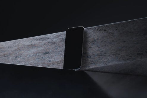 Minimalist phone resting on weathered concrete surface against black background