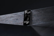 Phone with text overlay positioned on rough concrete architectural element dark scene
