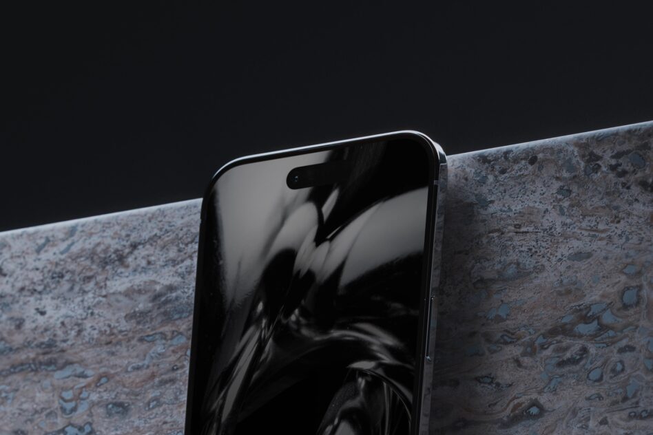 Device leaning against textured concrete ledge with dark moody lighting setup
