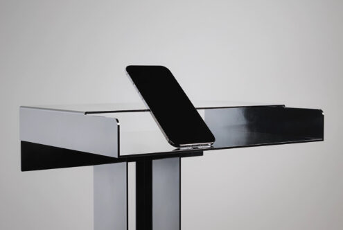Sleek black smartphone balanced on horizontal white shelf display stand
