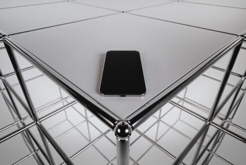 Dark smartphone centered on grid ceiling with chrome geometric frames