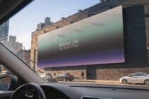 Car dashboard perspective of brick building with gradient digital billboard, Mockup Lab branding visible