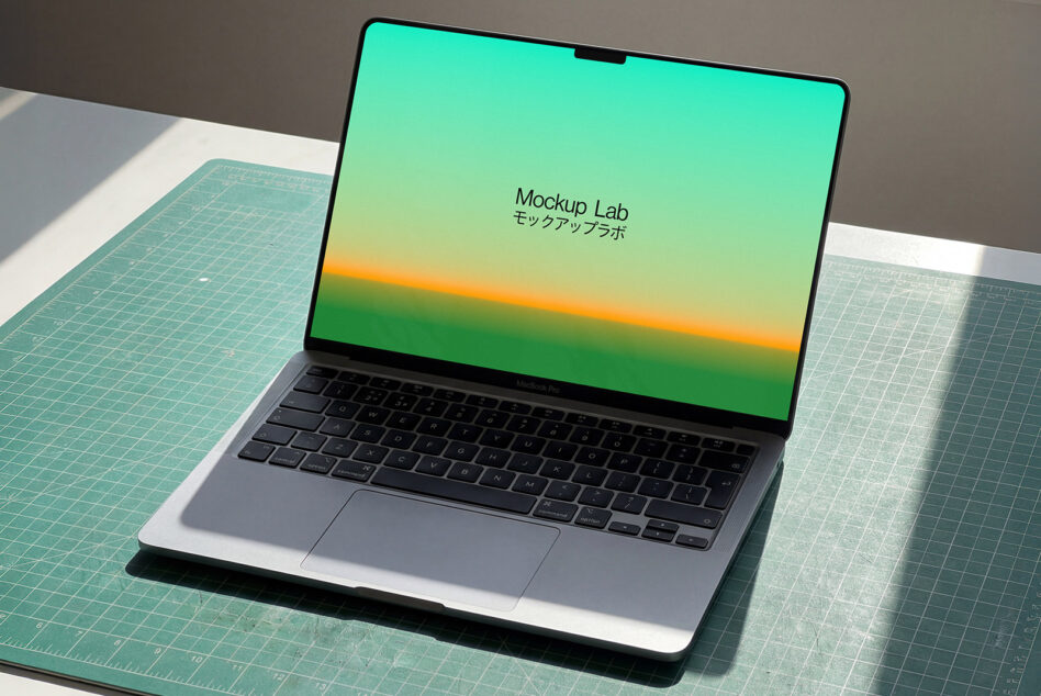 MacBook Pro with green yellow gradient display on craft cutting mat