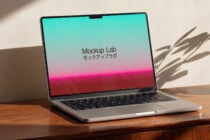 Laptop displaying cyan to pink gradient, angled view with afternoon light