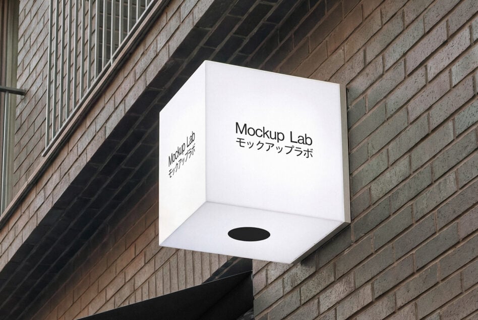 Illuminated 3D cube sign on urban brick wall with Mockup Lab bilingual text