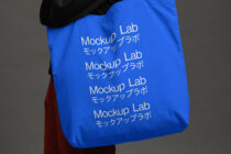 Cobalt blue tote with repeating white text held over shoulder