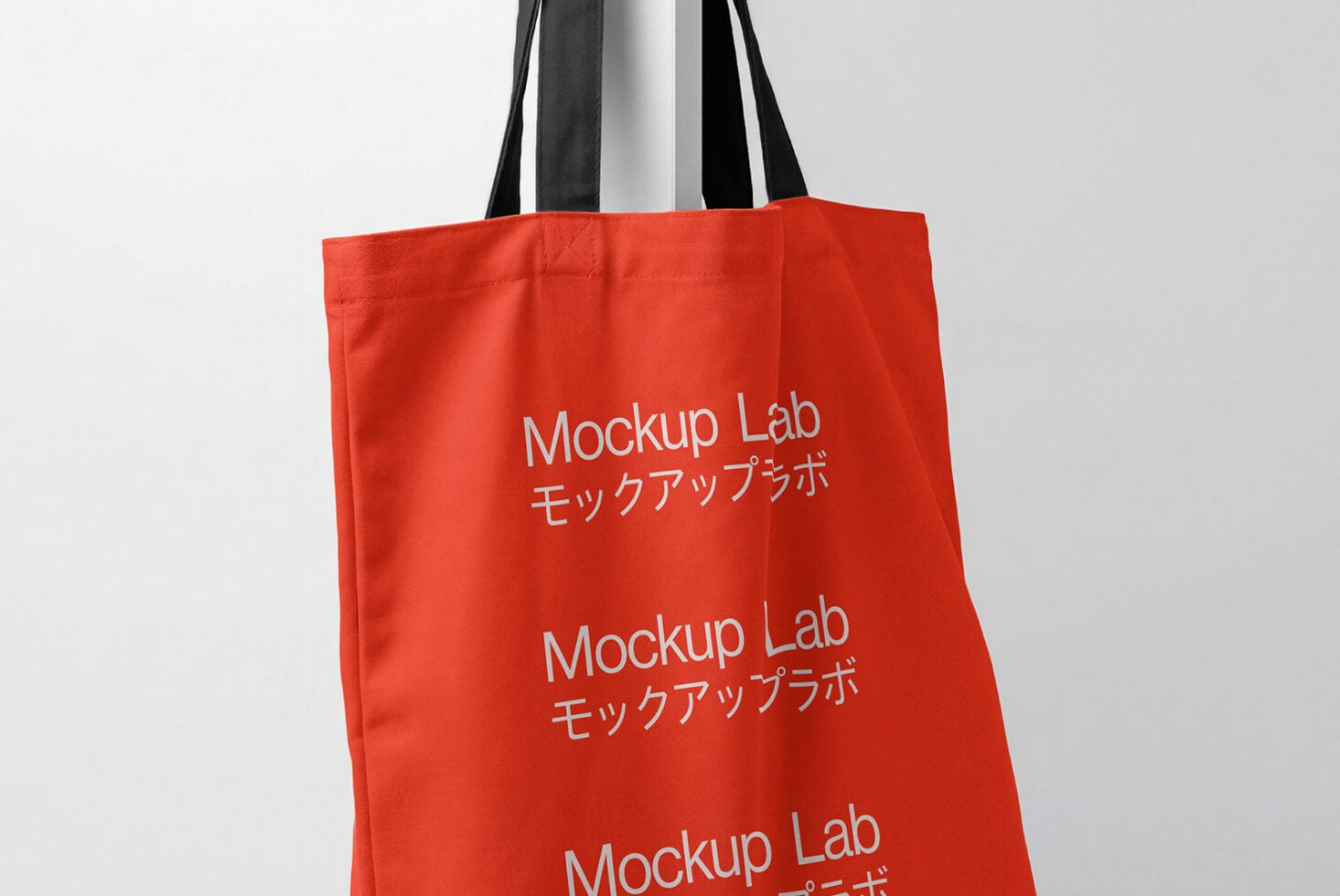 Red tote bag showing repeated branding text on front canvas surface