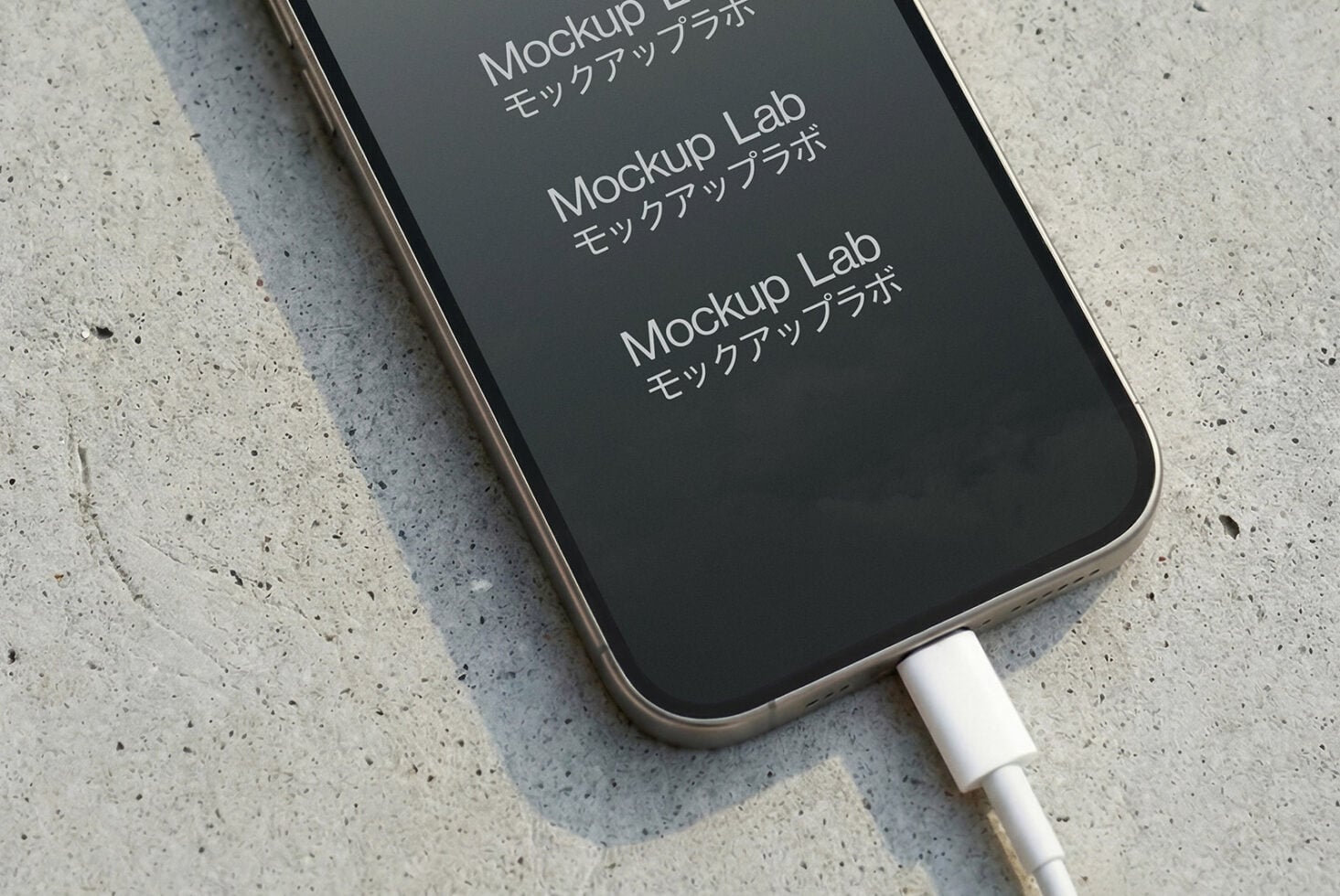 Charging phone on concrete from angle showing mostly dark screen display