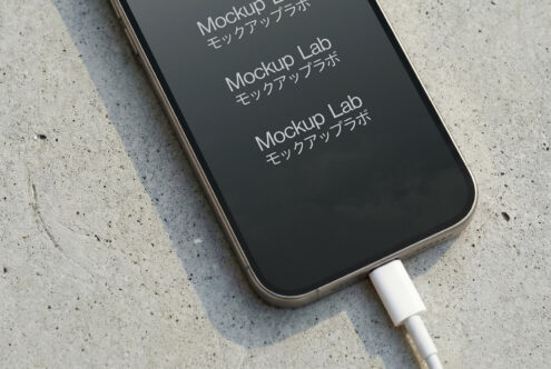 Charging phone on concrete from angle showing mostly dark screen display