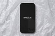 iPhone 14 Pro with black screen displaying Mockup Lab text on white textured background