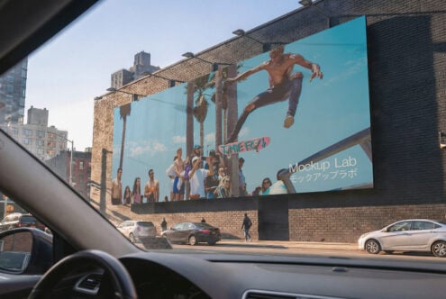 Car windshield view of urban billboard showing surfer jumping with palm trees, Mockup Lab text overlay